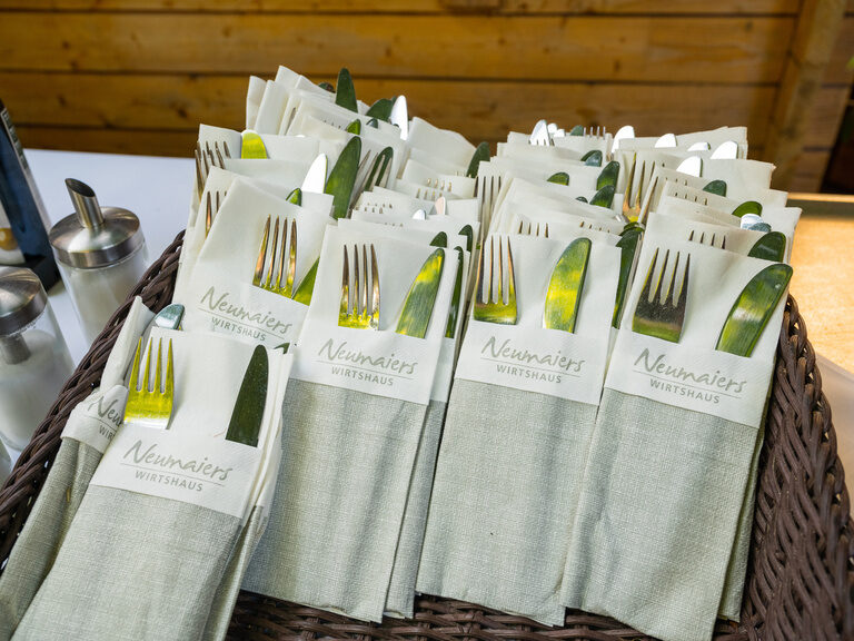 Ein Korb mit Besteck auf einem Tisch im Biergarten des Neumaiers WIRTSHAUS.