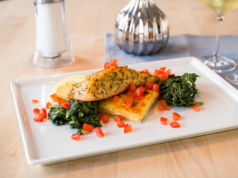Ein kunstvoll angerichteter Teller mit frischen Zutaten auf einem Holztisch.